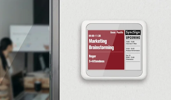 SyncSign e-paper meeting room display mounted outside an office room